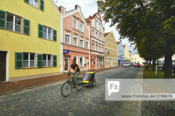 Fahrradfahrer auf Straße Strasse mit Kopfsteinpflaster in Dorfen Oberbayern Deutschland