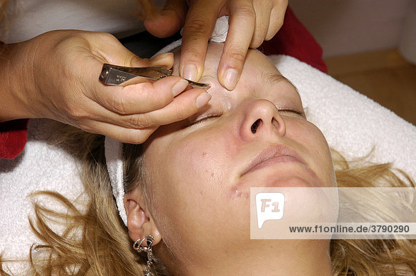 Young woman at a cosmetics treatmen  hygiene  groom eyebrows  trim eyebrows  tweezers