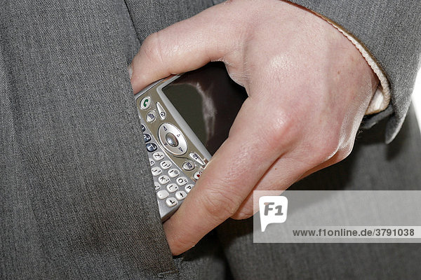 Business manager inserts mobile phone in his pocket