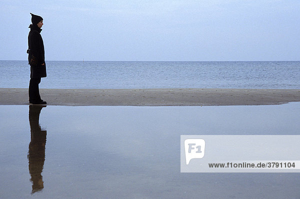Body reflection - Woman stands on sandy beach at the sea