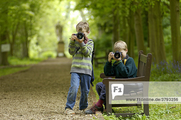 Ten and eight year old boys taking pictures in a park