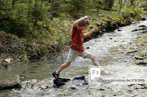 One seven-year-old boy jumping over brook