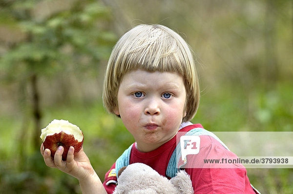 Ein dreijähriges Mädchen isst einen Apfel