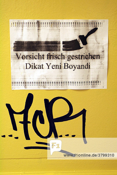 Frisch gestrichene gelbe Wand in einer U-Bahn Station wurde bereits durch Grafitti tak uebermalt. Ein zweisprachiger Hinweis auf die frisch gestrichene Wand wurde uebersehen.