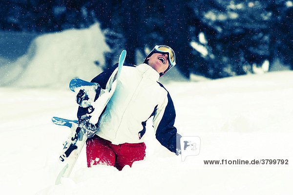 Laughing snowboard girl in action with waist-high snow bulk (Saalbach  Austria)