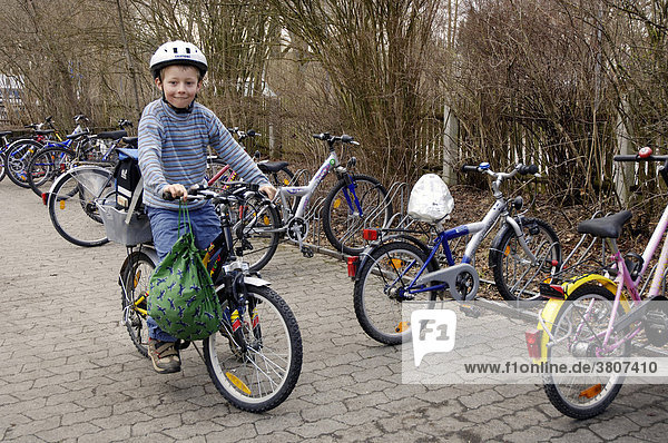 Eight-year-old boy with helmet on bicycle at bicycle stand