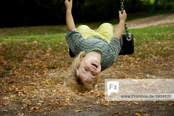 Little girl swinging upside down in a playground
