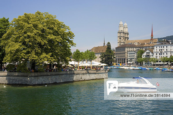 Zürich am Zürichsee  Schweiz. Im Hintergrund das Grossmünster. Terrassenrestaurant unter schattenspendenden Bäumen. Motorboot mit Schweizerflagge.