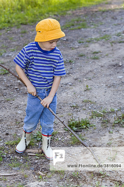 Ein vierjähriger Bube spielt mit einem Stock