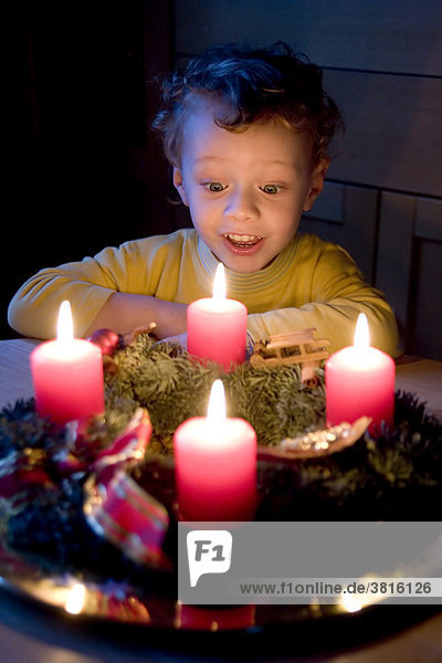 Ein drei Jahre alter Bube bestaunt einen Weihnachtskranz