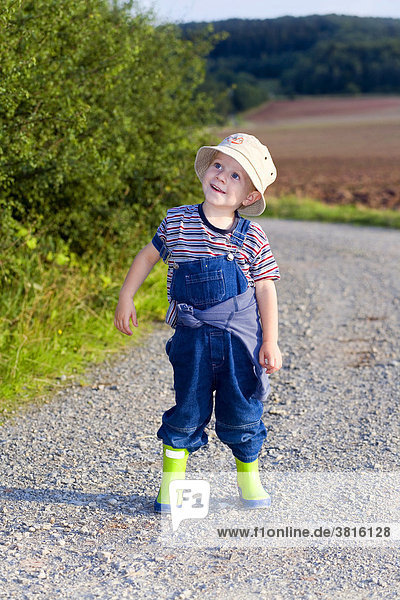 A three years old boy with rubber boots and a slouch hat