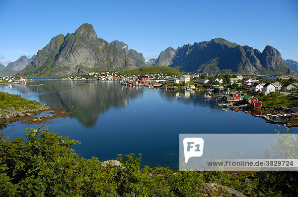Berge und Häuser spiegeln sich im Fjord Reine Moskenesöya Lofoten Norwegen