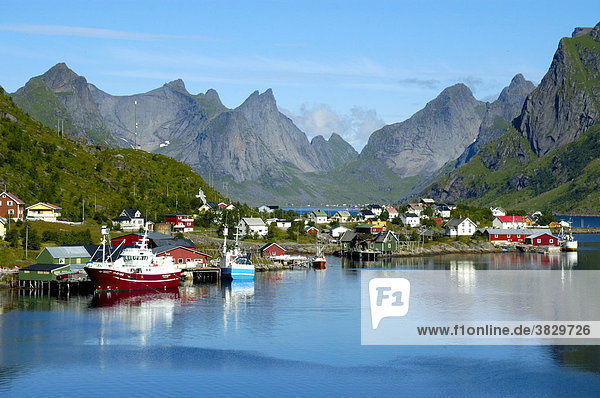 Berge Schiffe und Häuser spiegeln sich im Fjord Reine Moskenesöya Lofoten Norwegen