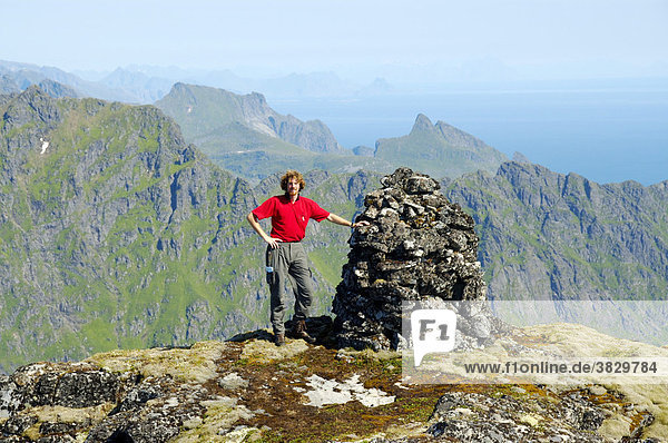 MR mountaineer at stoneman on the summit of mountain Mannen Moskenesoya Lofoten Norway