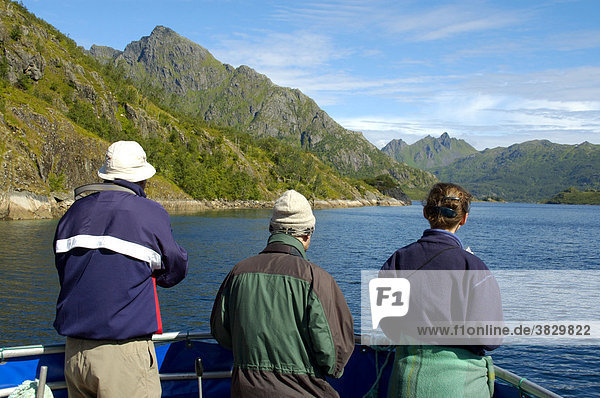 MR three people standing in the bow of a boat watching the scenic landscape Lofoten Norway