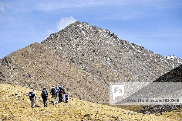 Trekking group passes a meadow below a high mountain in Tsotup-chu valley Tibet China