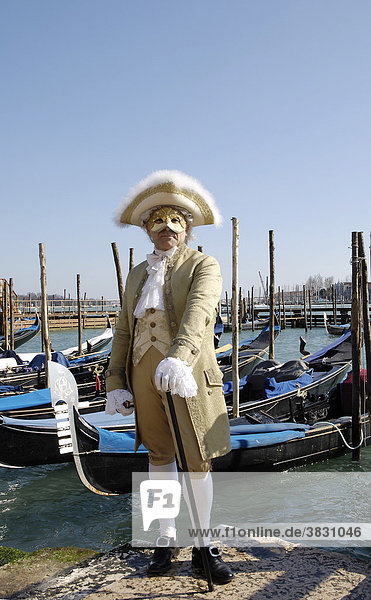 Mann in traditioneller alter Kleidung und Maske vor Gondeln beim Karneval in Venedig  Italien
