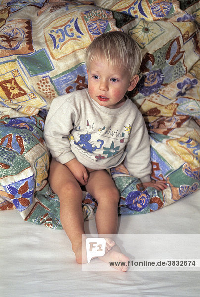 Kleiner Junge sitzt im Bett