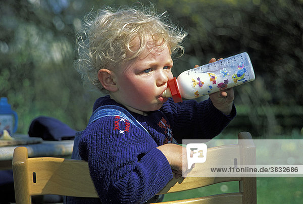 Zweijähriger Junge trinkt aus Milchflasche