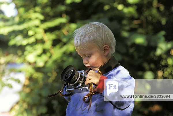 Eineinhalbjähriger Bub mit Fotoapparat