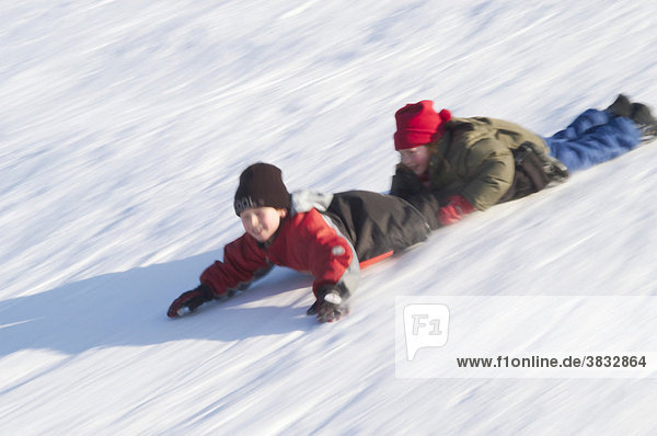 Children sliding on their belly downhill
