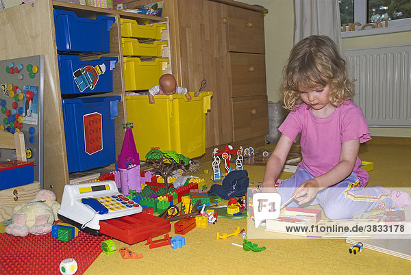 Kleines Mädchen spielt in ihrem chaotischen Kinderzimmer