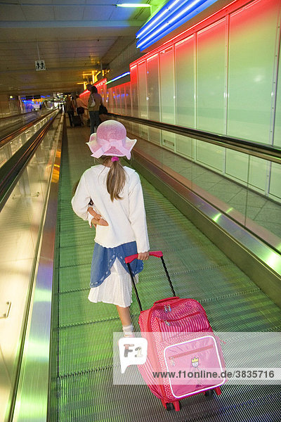 Kleines Mädchen mit Puppe und Trolley am Flughafen München