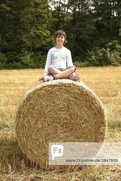 Mädchen  8 Jahre  sitzt auf Strohballen