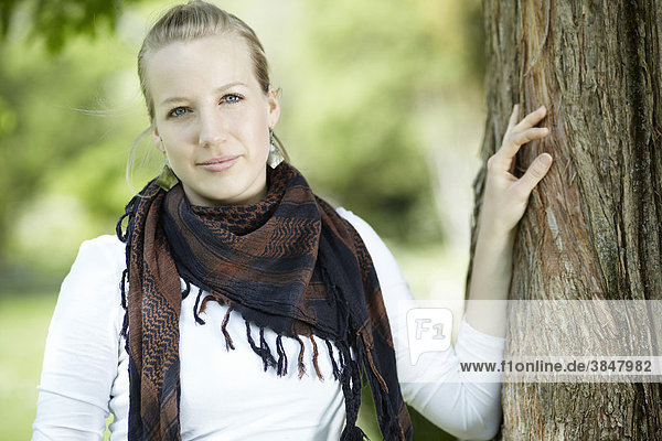 Junge Frau mit Halstuch  Hand an Baumstamm gestützt  Portrait