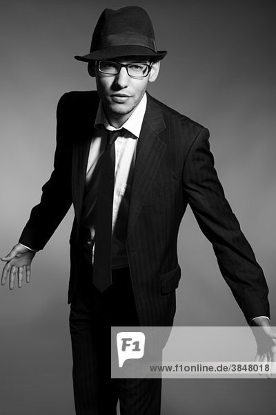 Portrait of a young man with glasses  suit  shirt  tie and hat  provocative view