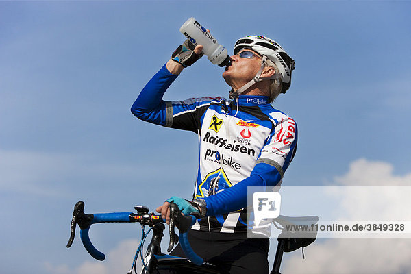 Agiler Senior beim Rennradfahren  trinkt Wasser