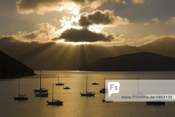 Sonnenstrahlen über dem Hafen von Akaroa im Morgenlicht  Boote im Gegenlicht  Banks Peninsula  Region Canterbury  Südinsel  Neuseeland