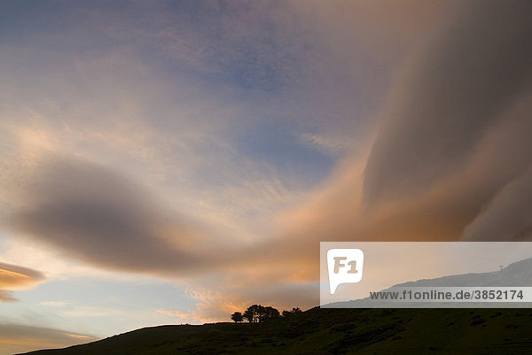 Dramatischer Wolkenhimmel bei Sonnenuntergang  in der Nähe vom Tunnel Beach  South Island  Neuseeland