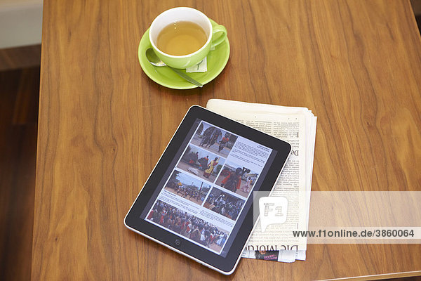 EBook Lesegerät iPad mit Teetasse und Tageszeitung auf Holztisch
