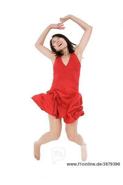 Beautiful Asain woman in a red sundress jumping on a white background