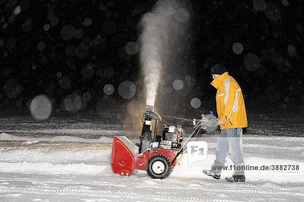 Mann arbeitet mit der Schneefräse  schneefreier Gehweg am Morgen