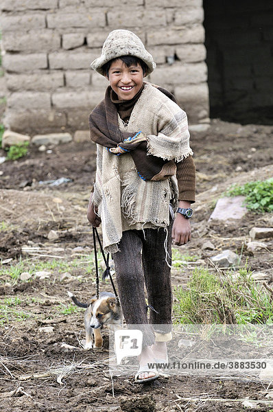 Shepherd boy in traditional dress with puppy on a leash  Altiplano Bolivian highland  Oruro Department  Bolivia  South America