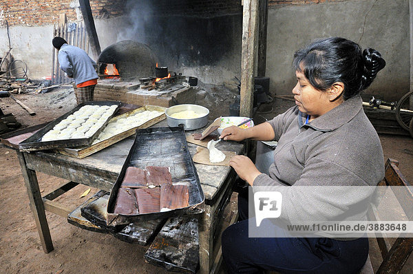 Bäckerin in Hinterhofbäckerei im Morgengrauen bereitet Brötchen zum Backen im traditionellen Holzofen vor  San Ignacio  Chiquitania  Departamento Santa Cruz  Bolivien  Südamerika