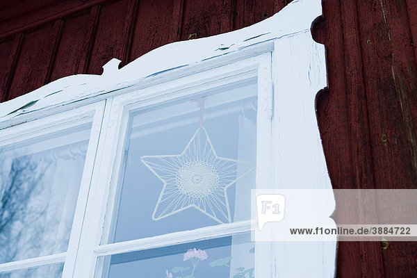 Sternförmiges Ornament hängend im Fenster des Hauses