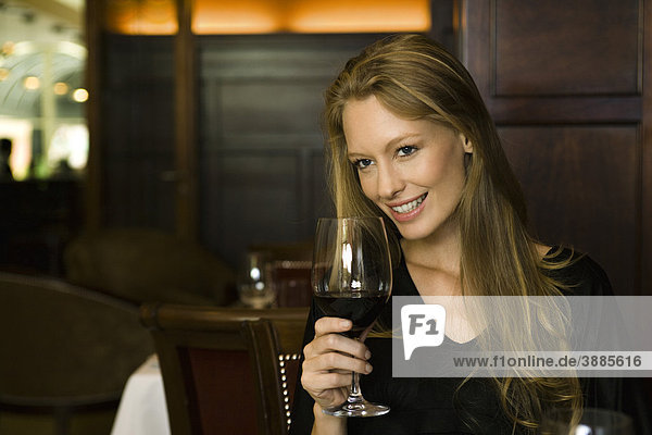 Frau genießt ein Glas Rotwein im Restaurant
