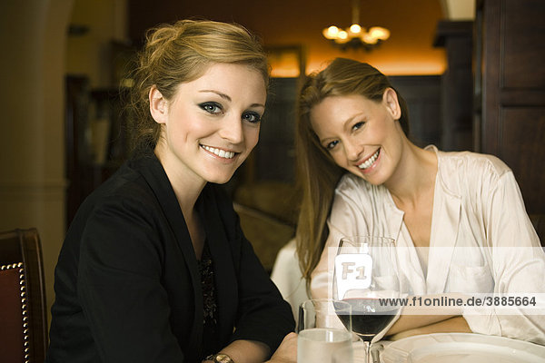 Frau bei einem Glas Wein mit Freundin im Restaurant
