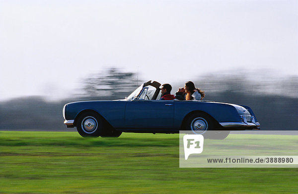 People riding in convertible car