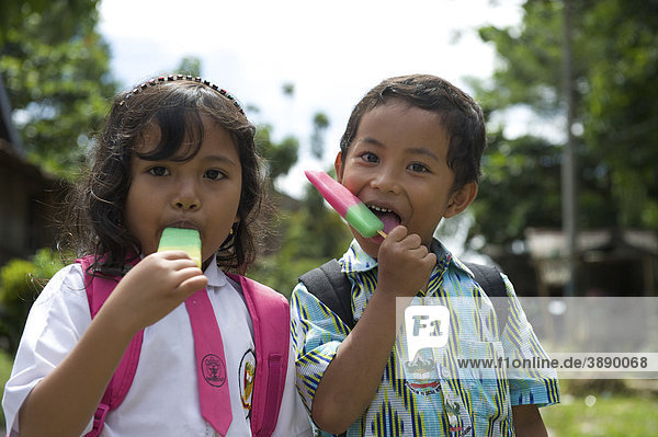 Mädchen und Junge beim Eisessen auf einer Straße in Rantepao  Sulawesi  Indonesien  Südostasien