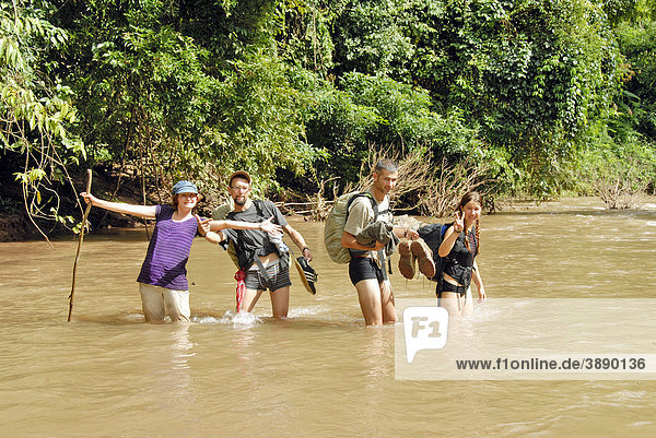 Gruppenaufnahme  Spaß  Trekking  Gruppe junger Touristen durchquert knietiefen Bach Nam Long  Distrikt und Provinz Phongsali  Laos  Südostasien  Asien