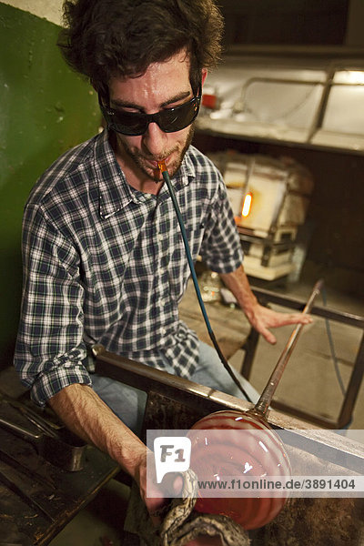 Paul Abowd shapes a glass bowl at the Michigan Hot Glass Workshop  Detroit  Michigan  USA