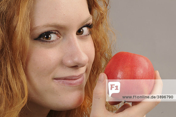 Gesicht einer rothaarigen Frau mit einem roten Apfel