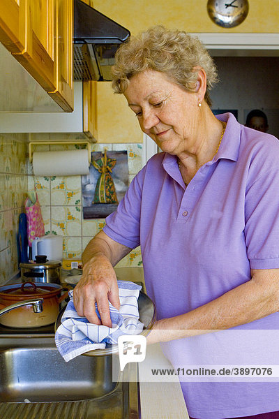 Pensionistin beim Geschirr abtrocknen
