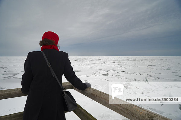Eine Frau sieht auf das Eis des Greifswalder Boddens in der Ostsee bei Lubmin  Mecklenburg-Vorpommern  Deutschland  Europa