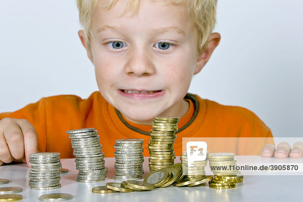Boy  5-years old  playing with euro coins  symbolic picture for price drop