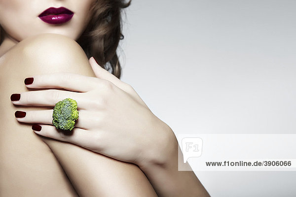 Junge Frau mit einem Ring aus Brokkoli  Schmuck mund